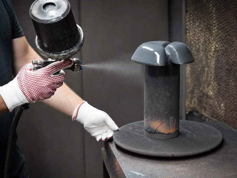 Rhedach Manufaktur: Entlüfterhaube wird in der Lackierkabine mit der Spritzpistole beschichtet