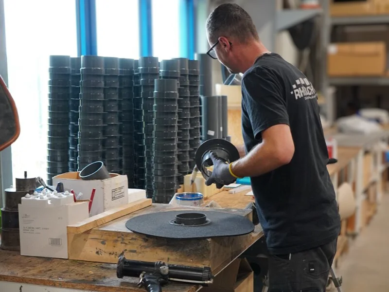 Rhedach Manufaktur: Mitarbeiter montiert eine Manschette am Werktisch, davor Kartuschenpistole und Dachdurchführung